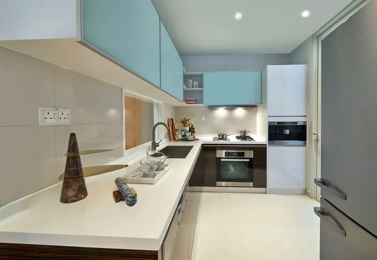 The Residences at W Sentosa Cove, photograph: an enclosed kitchen with white stone counters, a built-in oven, hob and pale blue upper cabinets