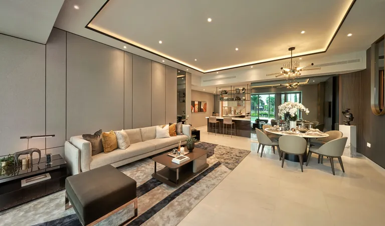 The Residences at W Sentosa Cove, photograph: a ground-floor living and dining room with a long sofa, a round dining table and full-height glass opening to a planted terrace