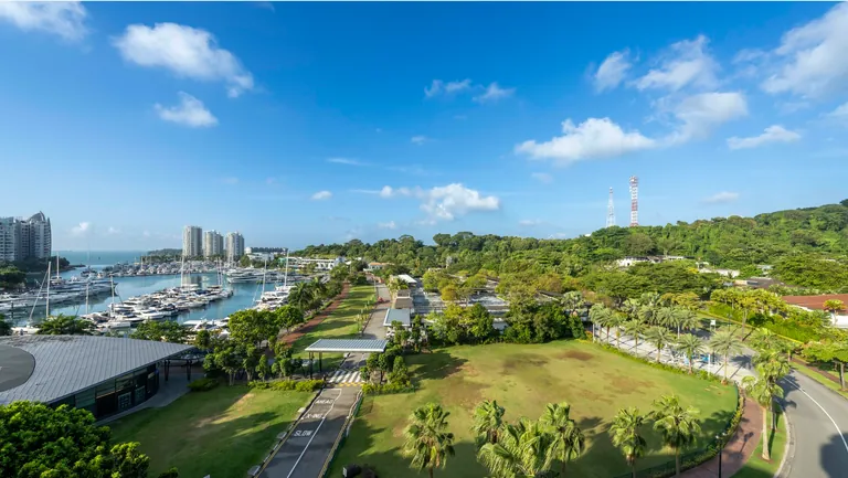 The Residences at W Sentosa Cove, photograph taken from a sixth-storey home: the yachts of the marina at Sentosa Cove, palms and lawns along Ocean Way, the sea and distant towers on the horizon