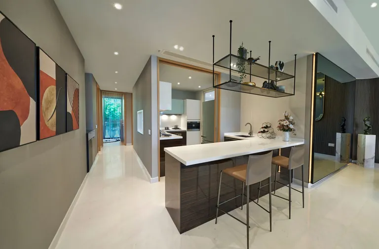 The Residences at W Sentosa Cove, photograph: an open kitchen with a white stone island counter, bar stools and a corridor leading to the garden